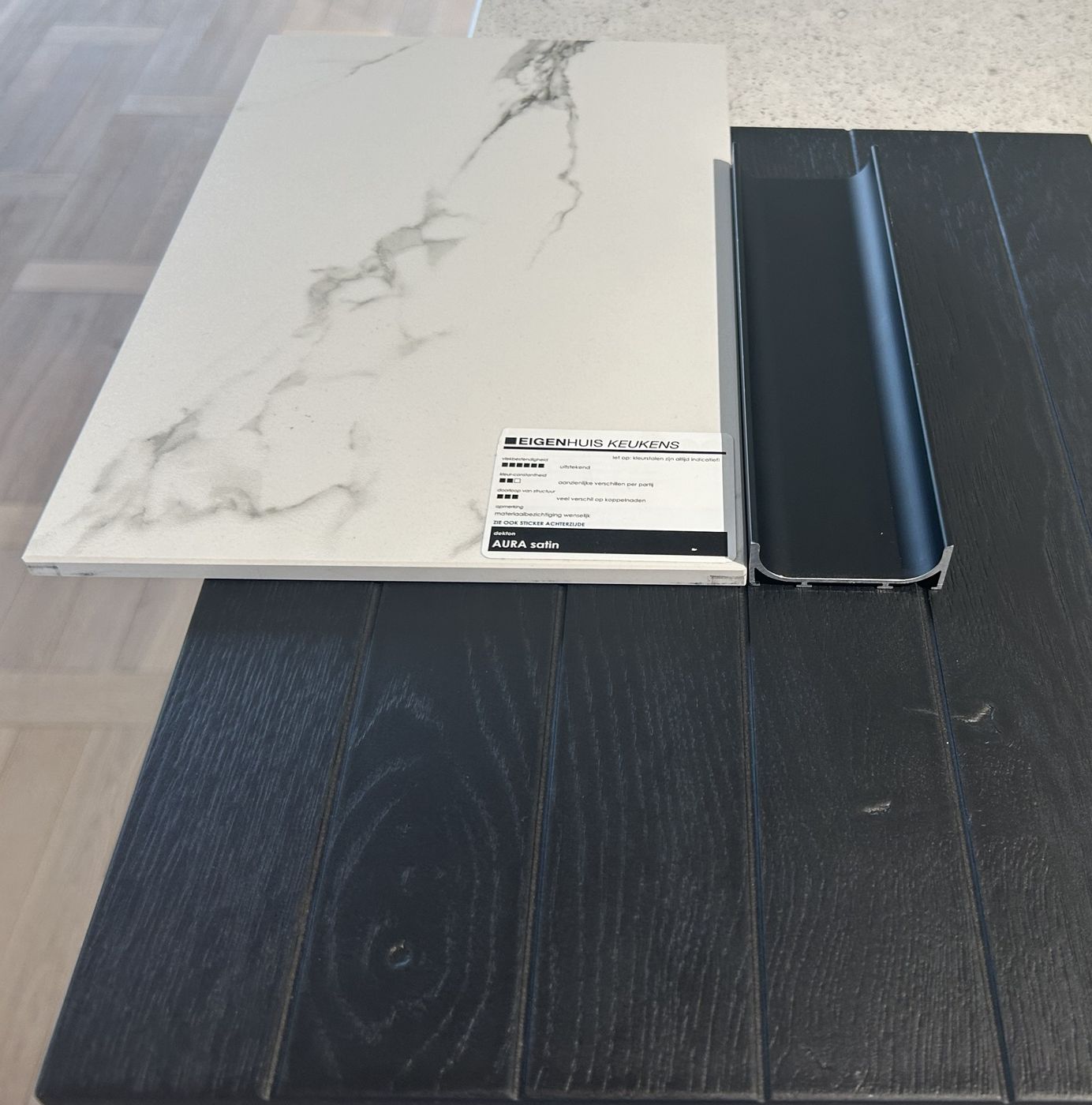 Materiaalstalen: wit Dekton-werkblad in marmerlook en zwart eikenfineer front